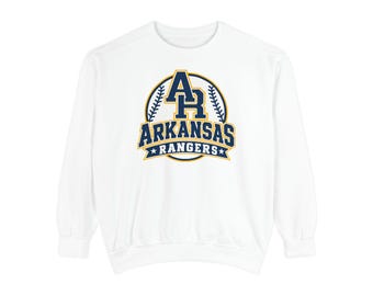 May include: A white long-sleeve sweatshirt featuring a central graphic with the text AR ARKANSAS RANGERS in navy blue and gold. The design is enclosed in a circular frame resembling a baseball with stitching details and two small stars.
