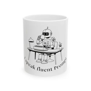May include: White ceramic mug featuring a black and white illustration of a robot at a desk, drinking from a mug. The robot is typing on a keyboard. The text "I speak fluent Prompt!" is printed around the mug.