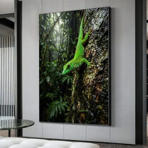 Könnte beinhalten: Ein lebhaft grüner Gecko klammert sich an einen strukturierten Baumstamm in einem üppigen, grünen Wald. Der Eidechsenkörper ist mit kleinen roten Punkten versehen. Dieses Kunstwerk ist ein Naturdruck, ideal für jeden Raum.