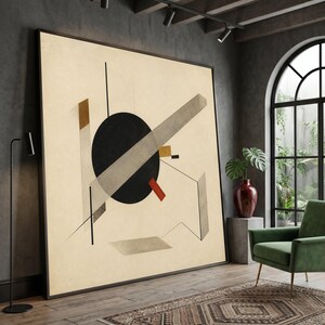 May include: A large square framed wall art piece featuring a beige background with a central black circle, intersecting gray rectangular bars, a small red rectangle, and thin black lines arranged in a geometric composition.