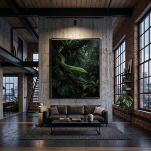 May include: A framed art print depicting a bright green snake with yellow eyes in a dense, dark green jungle setting. The artwork is displayed above a dark grey leather sofa in a modern loft apartment.
