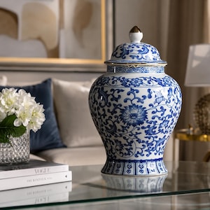 Könnte beinhalten: Eine blau-weiße Keramik-Ingwer-Vase mit Deckel. Die Vase hat ein blaues Blumenmuster auf weißem Grund. Der Deckel ist mit einem goldfarbenen Knauf versehen. Die Vase steht auf einem Glastisch.