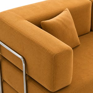 May include: A mustard yellow corduroy sofa featuring a textured ribbed fabric surface, a matching square throw pillow, and a polished silver-toned metal frame that supports the armrest and side structure of the furniture piece.