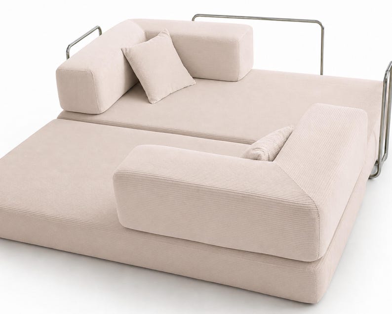 May include: A light beige corduroy modular sofa featuring a low-profile design with two rectangular backrests, two matching throw pillows, and a thin metallic frame structure that wraps around the perimeter of the seating area.