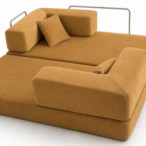 May include: A modular sofa bed upholstered in mustard yellow corduroy fabric. The piece features a low-profile design with two square cushions, two rectangular backrests, and a thin, silver-toned metal frame structure along the back and sides.