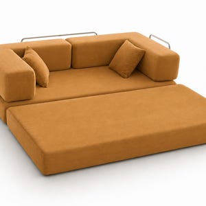 May include: A mustard yellow sofa bed with a textured fabric finish, featuring a low-profile design, two matching square throw pillows, and a silver-toned metal frame that wraps around the sides and back of the seating area.