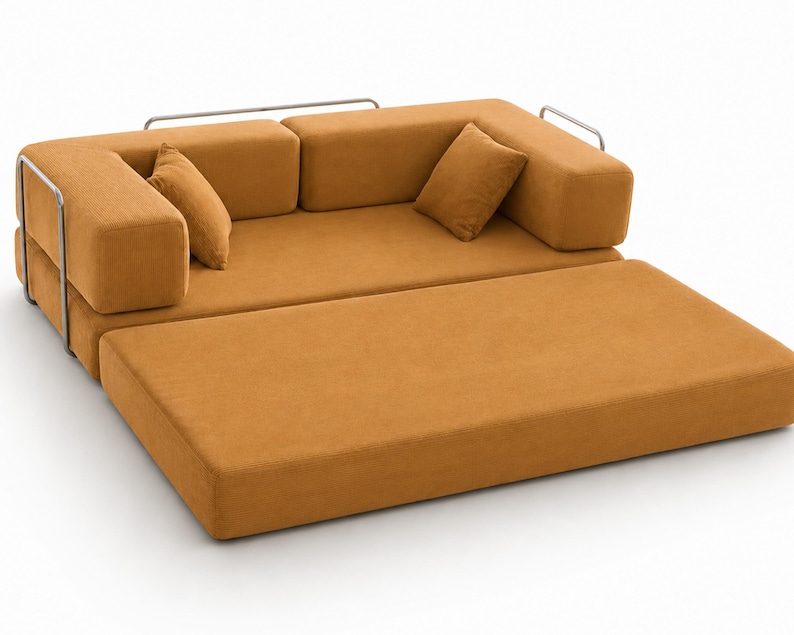 May include: A mustard yellow sofa bed with a textured fabric finish, featuring a low-profile design, two matching square throw pillows, and a silver-toned metal frame that wraps around the sides and back of the seating area.