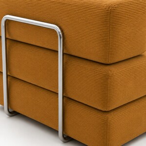 May include: A mustard yellow sofa section featuring a textured corduroy fabric upholstery. The piece is supported by a prominent, U-shaped polished chrome metal frame that wraps around the side of the thick, stacked rectangular cushions.