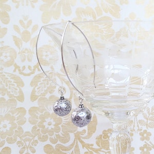 May include: A pair of silver hoop earrings with textured silver ball dangles.