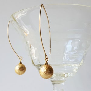 May include: A pair of gold dangle earrings with hammered gold ball charms.