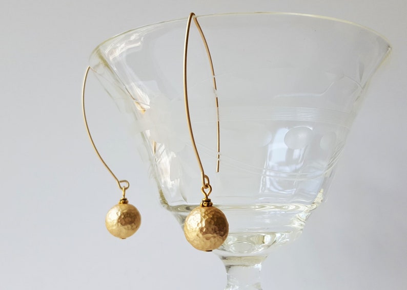 May include: A pair of gold dangle earrings with hammered gold ball charms.