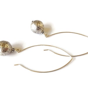 May include: A pair of silver hoop earrings with textured round silver beads hanging from the hoops.