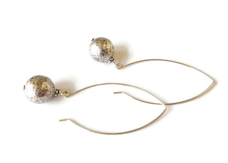 May include: A pair of silver hoop earrings with textured round silver beads hanging from the hoops.