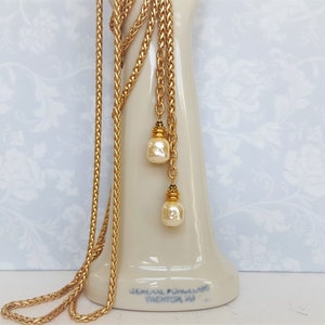 May include: A gold chain necklace with two pearl drops. The chain is braided and has a gold clasp.