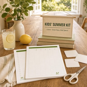 May include: A Kids' Summer Kit canvas wall hanging with green text, two stacked books, two white paper planners with green headers and grid lines, three small square note cards, and a pair of silver scissors with white handles.