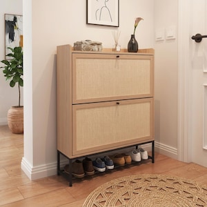 May include: A light wood shoe cabinet featuring two drop-down doors with textured rattan panels and small black knobs. The cabinet is supported by a black metal frame base, providing an open storage area underneath for several pairs of shoes.