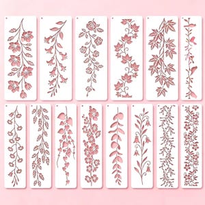 Könnte beinhalten: Ein Set aus zwölf rechteckigen weißen Schablonen mit verschiedenen botanischen und floralen Motiven, darunter Rosen, Ahornblätter, Kirschblüten, Ranken und kleine Vögel, jeweils mit einem kleinen runden Loch an der Oberseite zur Aufbewahrung.