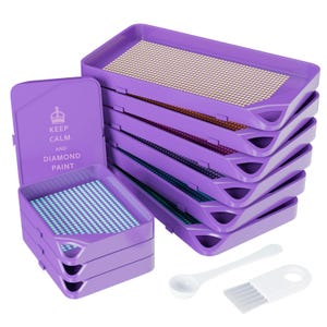 Könnte beinhalten: Ein Set aus violetten Kunststoffschalen für Diamond Painting, gestapelt in zwei Säulen, wobei ein Deckel den Text KEEP CALM AND DIAMOND PAINT trägt. Das Set enthält einen kleinen weißen Kunststofflöffel und ein weißes Kunststoffbürstenwerkzeug.