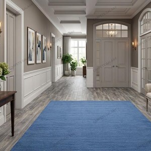 Solid blue hand-tufted wool rectangular area rug with medium Loop pile on wood flooring in a minimalist living room setting.