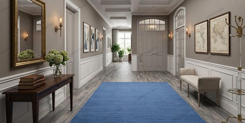 Solid blue hand-tufted wool rectangular area rug with medium Loop pile on wood flooring in a minimalist living room setting.