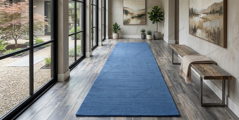 Solid blue hand-tufted wool rectangular area rug with medium Loop pile on wood flooring in a minimalist living room setting.