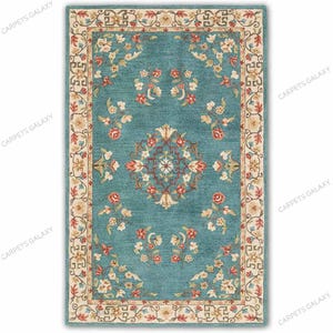 May include: A rectangular area rug featuring a teal blue field with a central floral medallion and scattered floral motifs in shades of red, cream, and green. The rug is framed by a cream-colored border with a repeating geometric pattern.