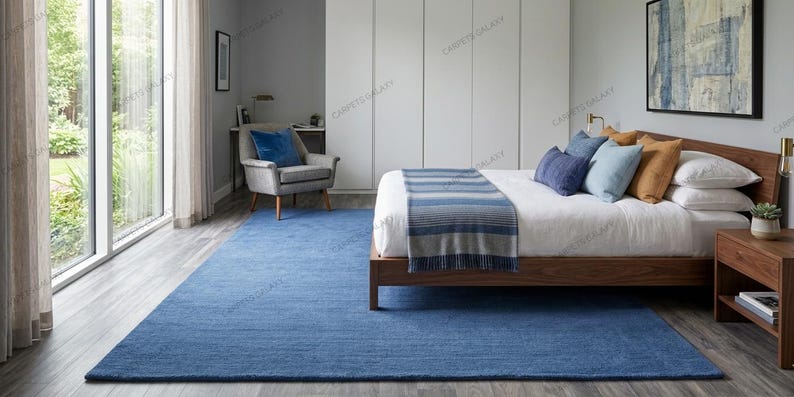 Solid blue hand-tufted wool rectangular area rug with medium Loop  pile on wood flooring in a minimalist living room setting.