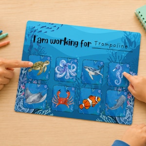 May include: A blue educational chart with illustrations of sea creatures, including a turtle, octopus, whale, seahorse, stingray, crab, clownfish, and shark. The text "I am working for Trampoline" is written on the chart. The chart is being pointed at by two hands.