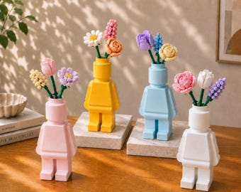 May include: Four plastic vases shaped like minifigure torsos in pastel pink, bright yellow, light blue, and white. Each vase holds a small bouquet of colorful, buildable plastic flowers with various petal shapes and green stems.