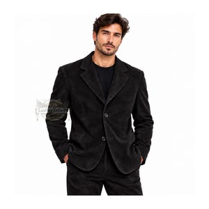 Könnte beinhalten: Ein schwarzer Wildlederblazer mit steigendem Revers, zwei Knöpfen auf der Vorderseite und langen Ärmeln. Die Jacke wird über einem schwarzen Hemd getragen und mit einer passenden schwarzen Wildlederhose kombiniert. Ein Logo mit Leather Tribe ist sichtbar.