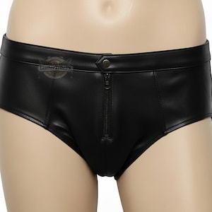 May include: Black leather-look briefs featuring a front vertical zipper closure, a single snap button at the waistband, and visible seam detailing. The garment includes a small circular logo on the left side with the text LeatherTribePK.