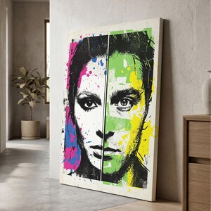 Pode incluir: Uma tela retangular com um retrato dividido. O lado esquerdo é em preto e branco com salpicos de tinta rosa e azul. O lado direito apresenta um retrato em preto e branco sobreposto com salpicos de tinta verde e amarela vibrantes.