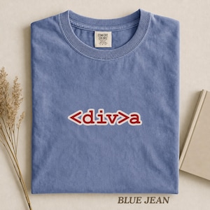 以下が含まれることがあります： ジーンズブルーの半袖Tシャツで、クルーネック仕様です。胸の中央には、白い縁取りが施された赤い文字で「<div>a」とプリントされています。首元の内側のラベルには、ブランド名「Comfort Colors」とサイズ情報が記載されています。