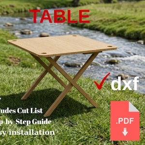 Puede incluir: Una mesa de picnic plegable de color marrón claro con una parte superior cuadrada y patas cruzadas, colocada sobre hierba verde cerca de un arroyo. La imagen incluye el texto "FOLDING PICNIC TABLE", "Diy", "Includes Cut List", "Step-by-Step Guide", "Easy installation", "dxf" y ".PDF".