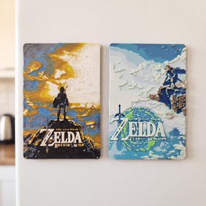 Puede incluir: Dos imanes rectangulares con ilustraciones de The Legend of Zelda. El imán izquierdo muestra la silueta de Link en un acantilado con el texto The Legend of Zelda Breath of the Wild. El imán derecho muestra un paisaje azul con el texto The Legend of Zelda Tears of the Kingdom.