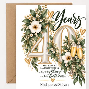 May include: A white greeting card featuring the number 40 in large, cream-colored font, surrounded by green leaves, white flowers, and gold hearts. Two champagne flutes are visible, with text reading Years, OF LOVE, LAUGHTER & everything in between, Michael & Susan.