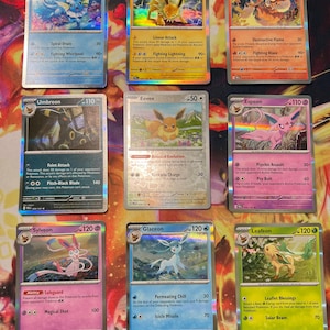 Könnte beinhalten: Eine Sammlung von neun Pokemon-Sammelkarten, die in einem drei-mal-drei-Raster angeordnet sind. Die Karten zeigen Vaporeon, Jolteon, Flareon, Umbreon, Eevee, Espeon, Sylveon, Glaceon und Leafeon mit individuellen Illustrationen und Text.