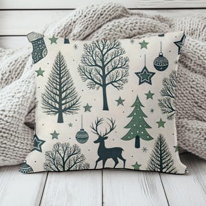 May include: A square throw pillow featuring a cream-colored background with a repeating pattern of dark green and forest green holiday motifs, including pine trees, deciduous trees, a silhouette of a deer, hanging ornaments, and various stars.