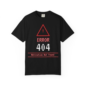 Könnte beinhalten: Schwarzes T-Shirt mit einem roten Warndreieck und dem Text "ERROR 404" in Weiß, darunter "Motivation Not Found". Das Design ist im Pixel-Stil gehalten. Das T-Shirt hat kurze Ärmel und einen Rundhalsausschnitt.