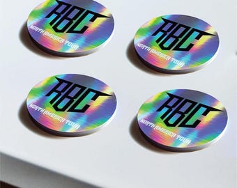 May include: Four circular stickers with a holographic, rainbow-colored background. Each sticker features the bold black text RBC and the words NORTH AMERICA TOUR printed in white below the main lettering.