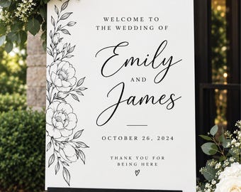 May include: A white rectangular wedding welcome sign featuring black floral line art on the left side. The text reads: WELCOME TO THE WEDDING OF Emily AND James OCTOBER 26, 2024 THANK YOU FOR BEING HERE with a small heart icon at the bottom.