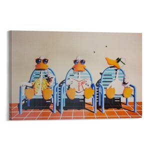 May include: A canvas print featuring three cartoon ducks relaxing in blue lounge chairs. The ducks wear sunglasses and are holding drinks and reading a magazine. The background is a light beige wall and a red-tiled floor.