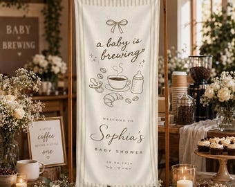 May include: A vertical cream-colored fabric banner with brown striped edges, featuring a bow, coffee cup, baby bottle, pacifier, and croissant illustrations. Text reads: a baby is brewing, WELCOME TO Sophia's BABY SHOWER, and 20.06.2026.