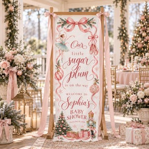 May include: A vertical banner featuring a pink ribbon, a ballerina, ballet slippers, a nutcracker, and a Christmas tree. The text reads: Our little sugar plum is on the way, WELCOME TO Sophia's BABY SHOWER, and December 20, 2026.