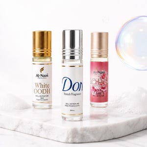 May include: Three clear glass roll-on perfume bottles with 6ml capacity. The left bottle has a gold cap and label reading Al-Naas White OODH. The centre bottle has a silver cap and label reading Don French Fragrance. The right bottle has a gold cap and label reading Lotus.