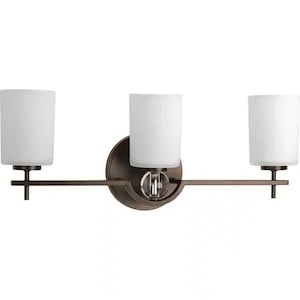 May include: A three-light vanity wall fixture featuring a dark bronze metal finish. The design includes a central circular mounting plate with a clear glass sphere accent and three cylindrical frosted white glass shades held by horizontal arms.