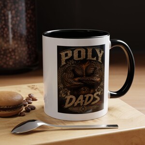 Peut inclure: Un mug en céramique blanc avec un intérieur et une anse noirs, présentant une impression graphique d'un torse musclé avec des tatouages tribaux traditionnels, le texte "POLY" en haut, "SAMOA" au centre et "DADS" en bas dans une police usée.