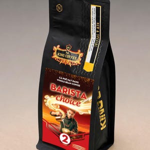 Puede incluir: Una bolsa negra de café en grano entero TNI King Coffee Barista Choice. El empaque presenta un gráfico de una persona sirviendo café, el texto "BARISTA choice", un número 2 grande y un logotipo de corona dorada. La bolsa está marcada New & Special.