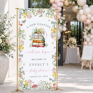 Puede incluir: Una pancarta rectangular vertical sobre un soporte de metal dorado con una pila de libros coronada por flores, rodeada por un borde de flores silvestres coloridas. El texto dice: A NEW CHAPTER will soon begin WELCOME TO EVERLY'S baby shower AUGUST 25, 20XX.