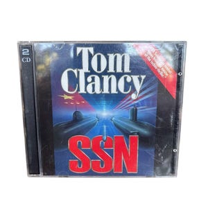 May include: A 2-CD jewel case for the Tom Clancy SSN video game. The cover features a dark blue background with two black submarines, a red banner in the corner with white text, and the title SSN in large red letters at the bottom center.